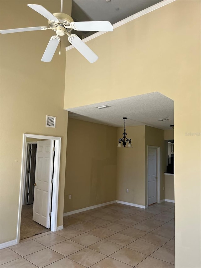 tiled empty room with ceiling fan with notable chandelier, crown molding, and a textured ceiling