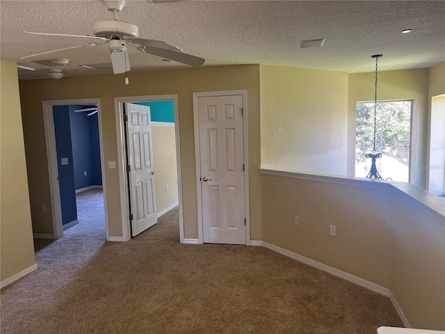 empty room featuring a textured ceiling, ceiling fan, and carpet floors