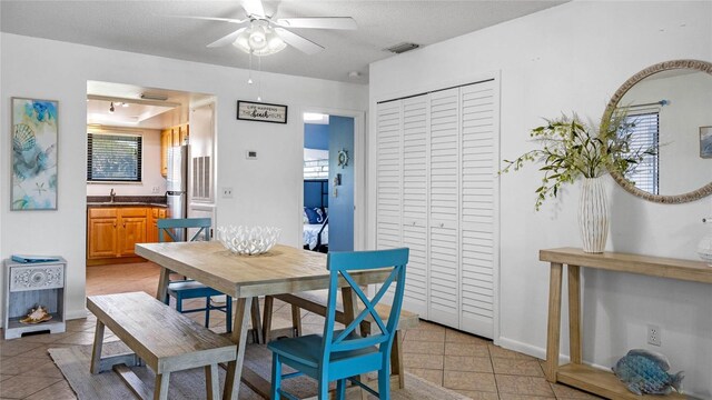 tiled dining space featuring a textured ceiling and ceiling fan