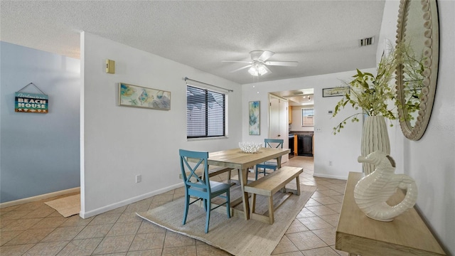 tiled dining room with a textured ceiling and ceiling fan