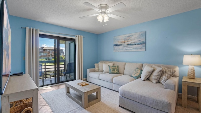 living room featuring ceiling fan, light tile patterned floors, and a textured ceiling