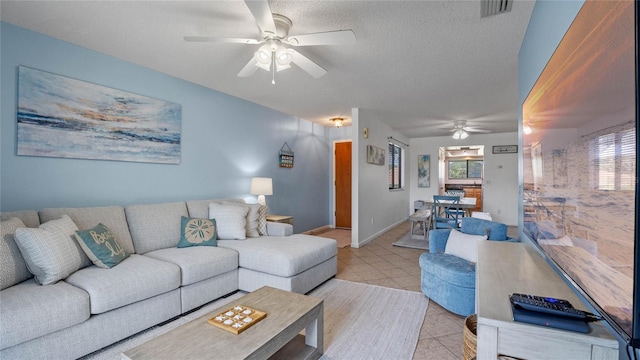 living room featuring a textured ceiling, light tile patterned floors, and ceiling fan