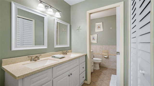 bathroom featuring tile patterned floors, vanity, toilet, and tile walls