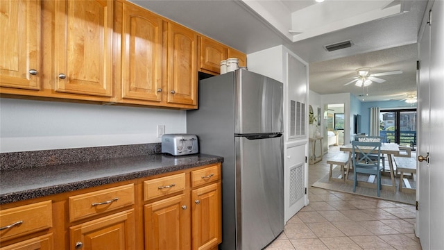 kitchen featuring stainless steel fridge, ceiling fan, light tile patterned floors, and a textured ceiling