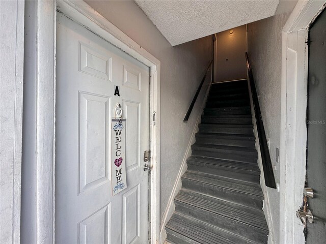 staircase featuring a textured ceiling