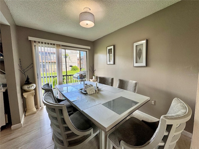 dining space featuring a textured ceiling and light hardwood / wood-style floors