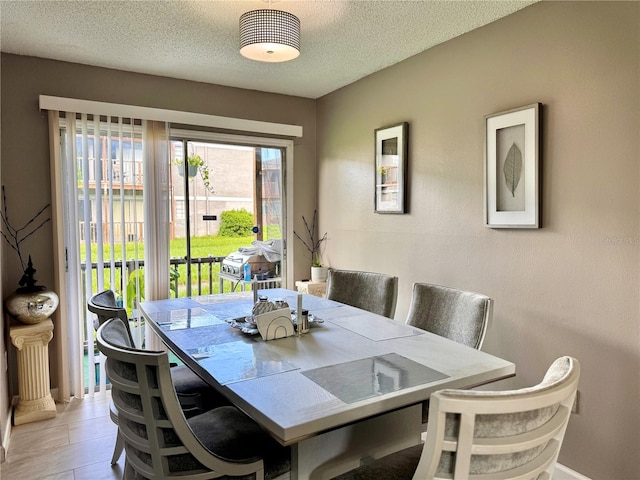 dining space with light wood-style flooring, baseboards, and a textured ceiling