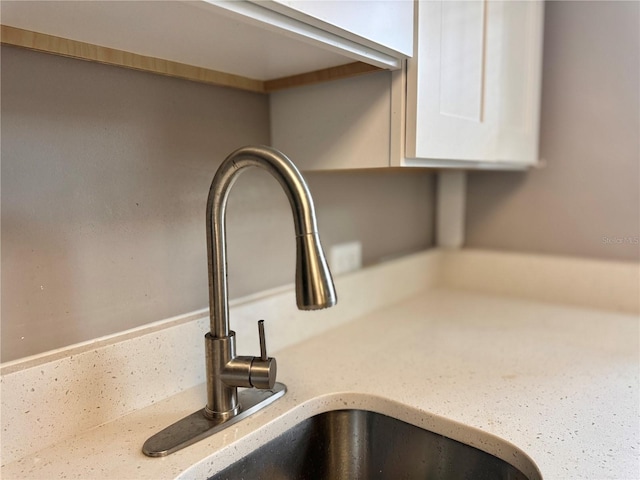 details featuring white cabinetry, light stone counters, and a sink