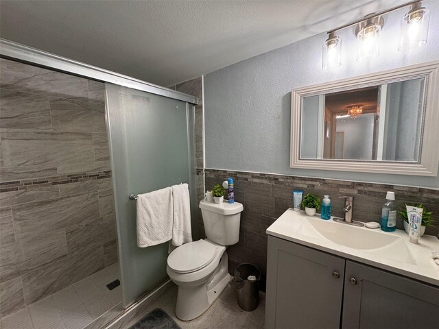 bathroom featuring toilet, walk in shower, vanity, backsplash, and tile walls