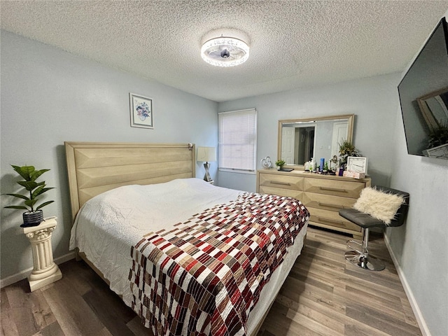 bedroom with a textured ceiling and wood-type flooring