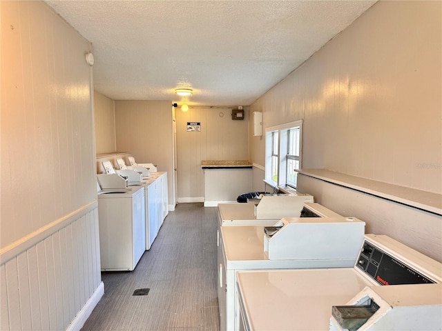 common laundry area with a textured ceiling, dark wood-style flooring, and washing machine and clothes dryer