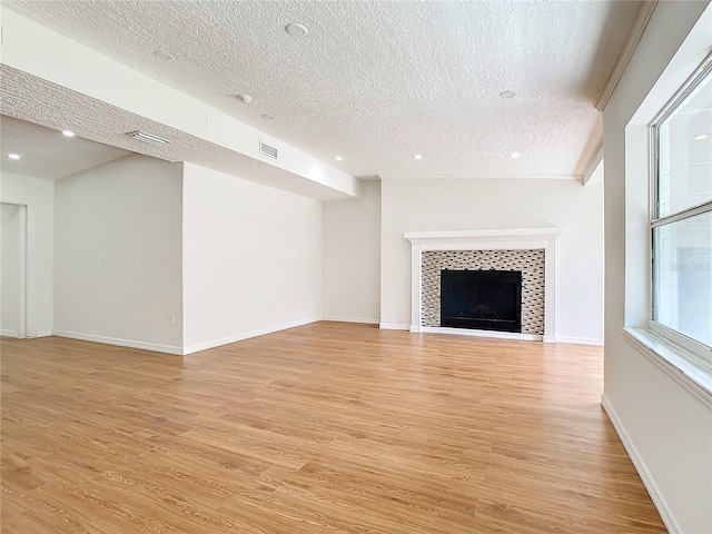 unfurnished living room with light hardwood / wood-style floors, a textured ceiling, and a fireplace