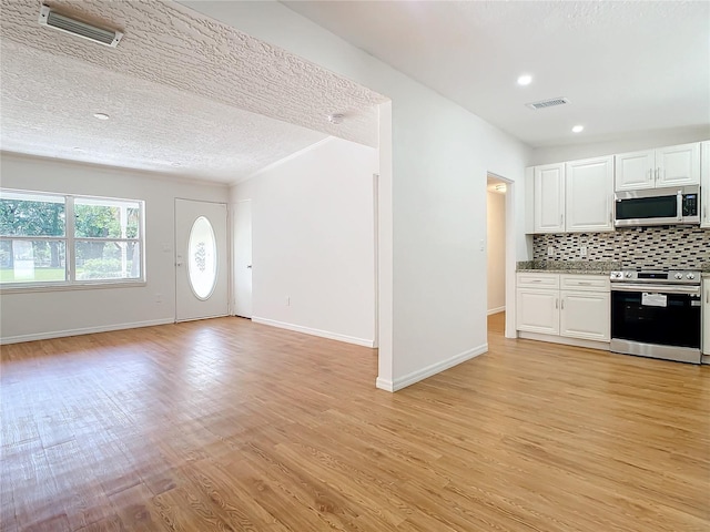 kitchen featuring appliances with stainless steel finishes, light hardwood / wood-style flooring, backsplash, a textured ceiling, and white cabinets