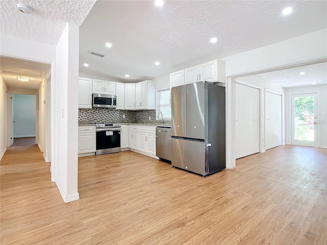 kitchen featuring backsplash, white cabinets, and stainless steel appliances