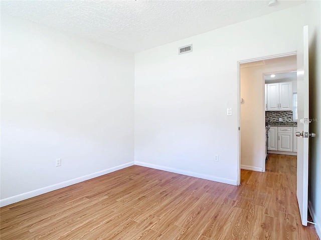 spare room with light hardwood / wood-style flooring and a textured ceiling