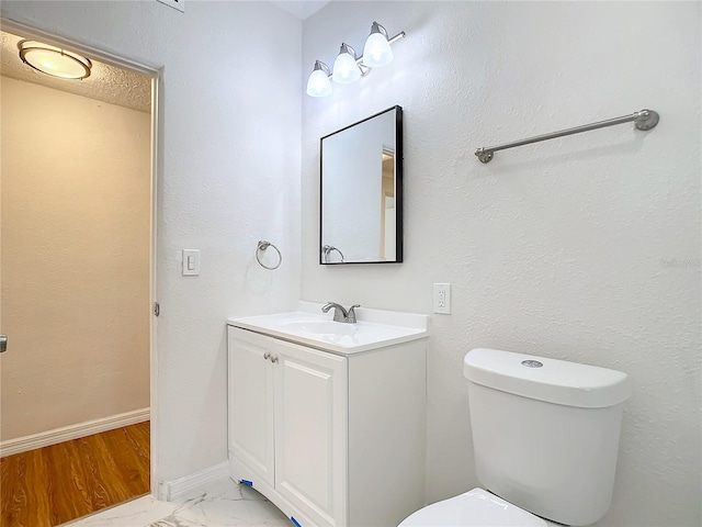 bathroom featuring a textured ceiling, toilet, and vanity