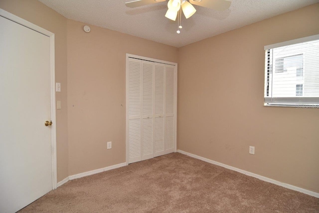 unfurnished bedroom featuring a closet, a textured ceiling, ceiling fan, and carpet floors