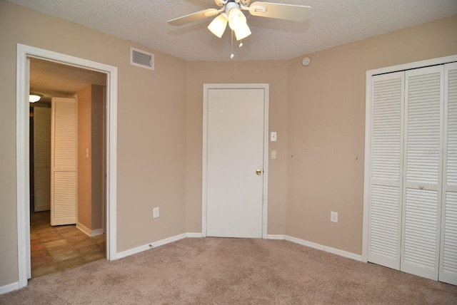 unfurnished bedroom with a closet, ceiling fan, light carpet, and a textured ceiling