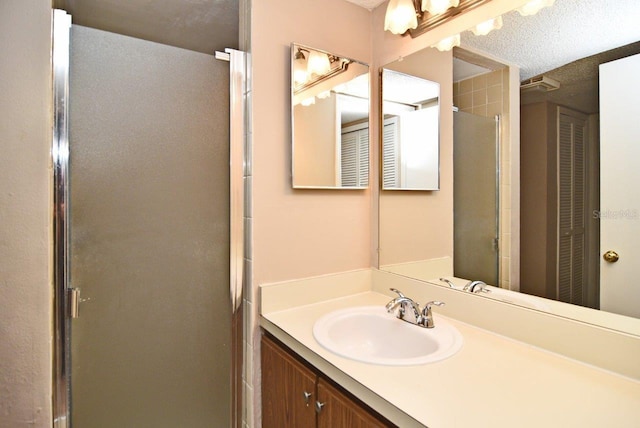 bathroom featuring a textured ceiling, vanity, and a shower with shower door