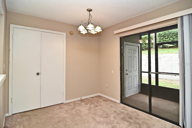 interior space featuring a textured ceiling, an inviting chandelier, and light carpet