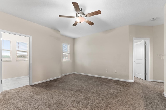 carpeted spare room with a textured ceiling, a healthy amount of sunlight, and ceiling fan