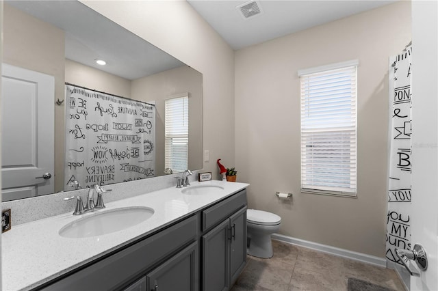 bathroom featuring a shower with shower curtain, vanity, toilet, and a healthy amount of sunlight