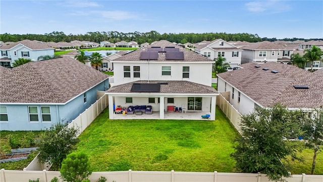 rear view of house with a patio area, a yard, and solar panels