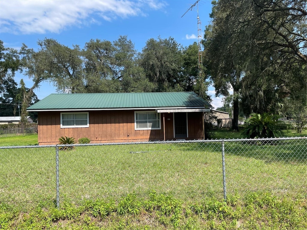view of front of house with a front lawn, metal roof, and fence