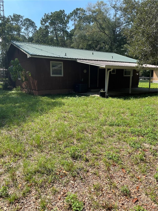 back of property featuring a yard and central AC