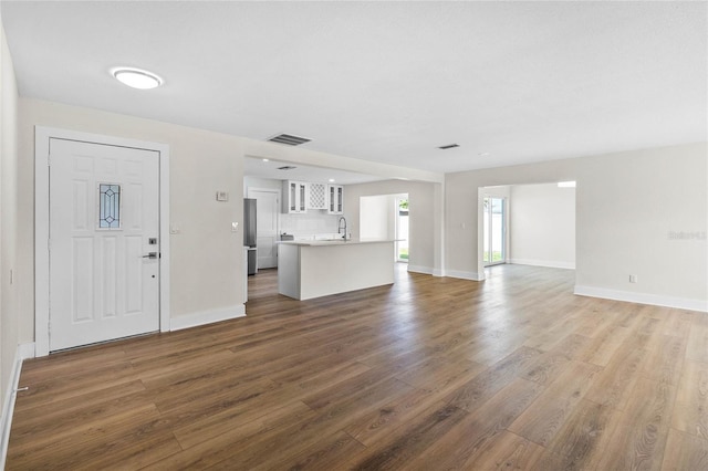 unfurnished living room featuring sink and dark hardwood / wood-style floors