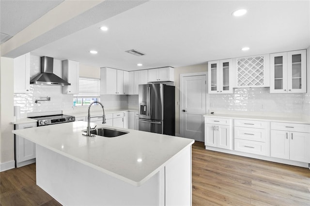 kitchen with stainless steel refrigerator with ice dispenser, wood-type flooring, sink, white cabinetry, and wall chimney range hood