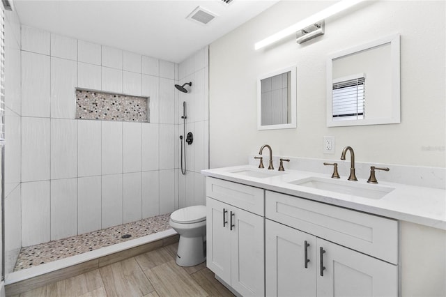 bathroom featuring tiled shower, toilet, and vanity