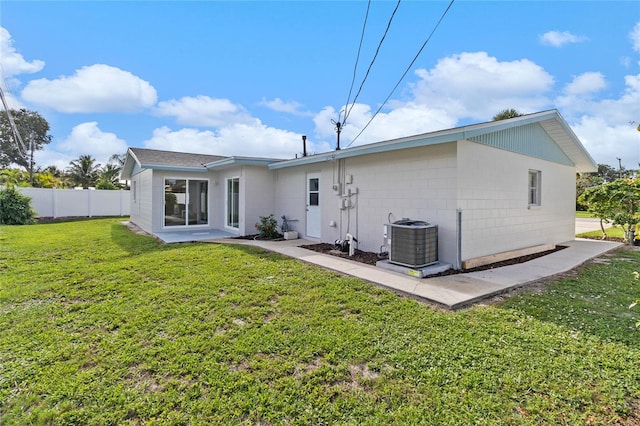 rear view of house featuring cooling unit and a yard