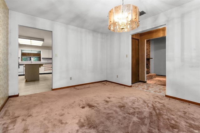 carpeted empty room featuring an inviting chandelier