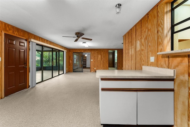 kitchen with a textured ceiling, wood walls, and ceiling fan