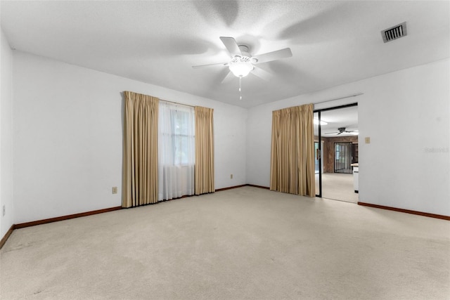 unfurnished room featuring light colored carpet, ceiling fan, and a textured ceiling