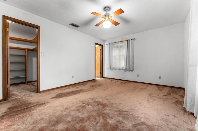 unfurnished bedroom with a closet, ceiling fan, light carpet, and a spacious closet