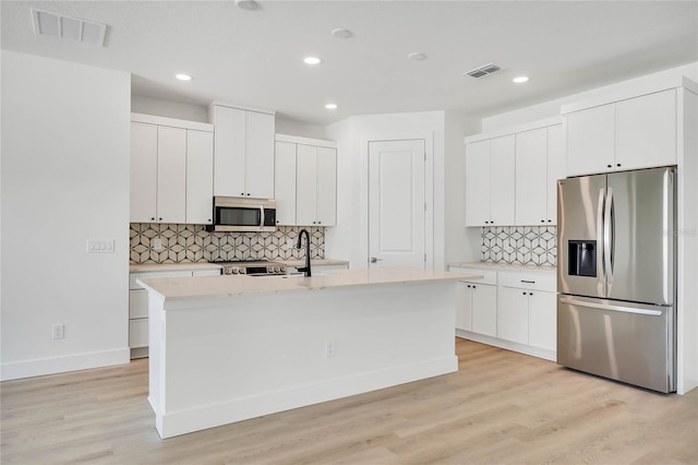 kitchen featuring light hardwood / wood-style floors, stainless steel appliances, and a center island with sink