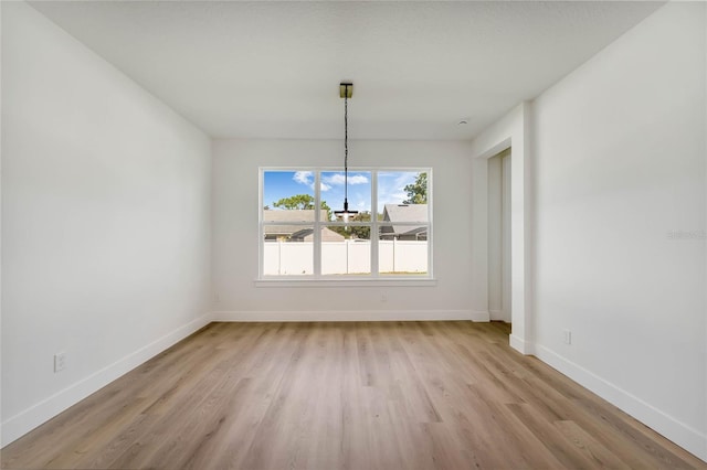 unfurnished dining area with an inviting chandelier and light hardwood / wood-style floors