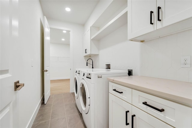 laundry area featuring washer and clothes dryer, cabinets, and light tile patterned floors