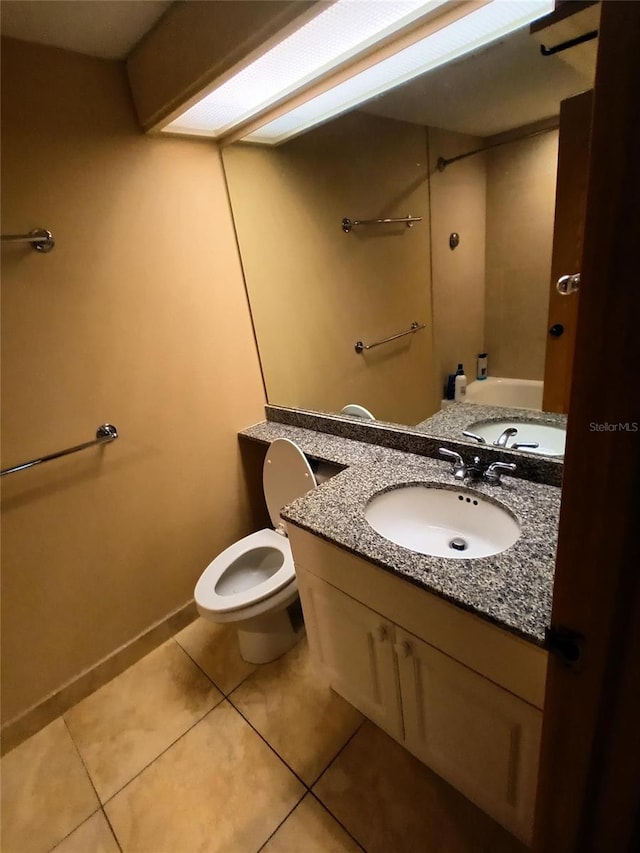 bathroom featuring tile patterned flooring, vanity, toilet, and a washtub