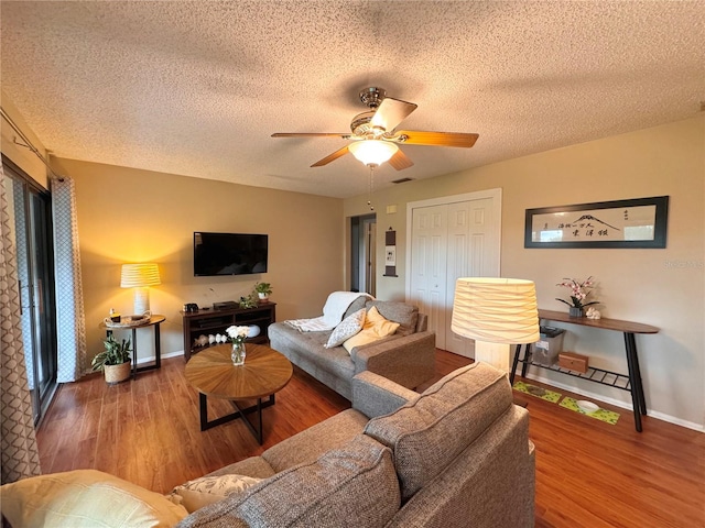 living room with a textured ceiling, ceiling fan, and hardwood / wood-style flooring