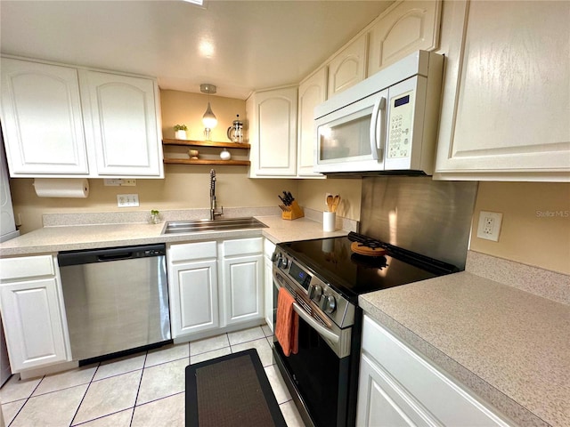 kitchen featuring sink, light tile patterned floors, appliances with stainless steel finishes, and white cabinetry