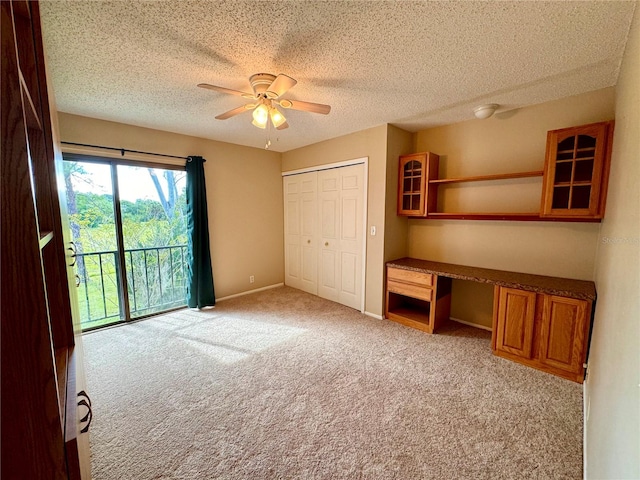 unfurnished bedroom featuring a closet, ceiling fan, light colored carpet, and a textured ceiling