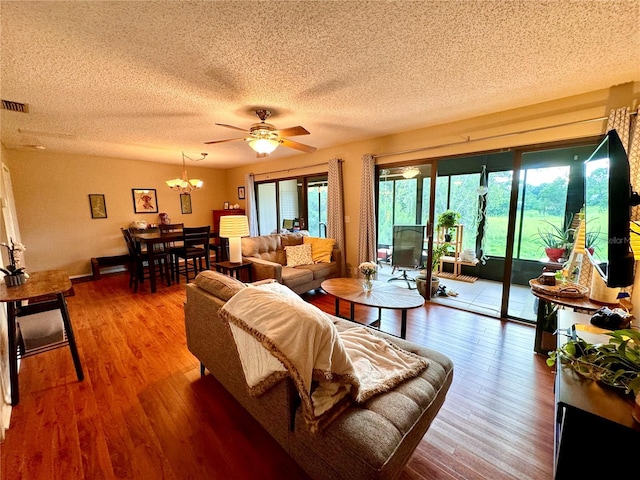 living room featuring ceiling fan with notable chandelier, a textured ceiling, and hardwood / wood-style floors