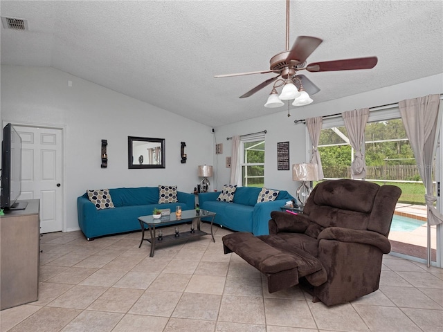 tiled living room with lofted ceiling, ceiling fan, and a textured ceiling