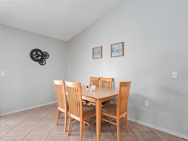 tiled dining space with a textured ceiling and vaulted ceiling