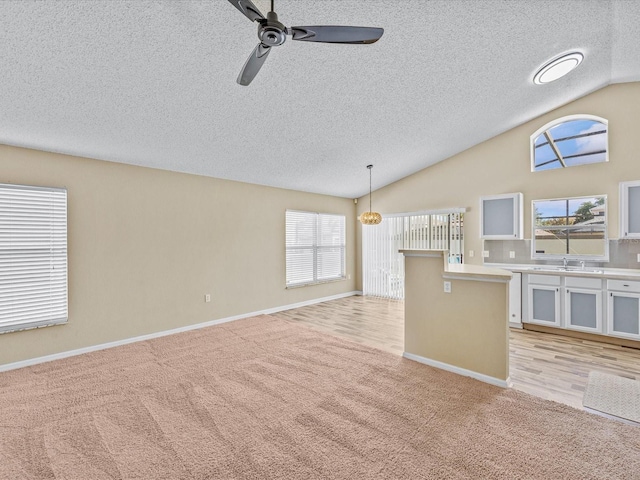 2977 Kokomo Loop, Haines City, FL 33844 - kitchen featuring light colored carpet, lofted ceiling, a ceiling fan, a textured ceiling, and light countertops