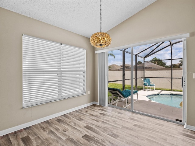 2977 Kokomo Loop, Haines City, FL 33844 - unfurnished dining area featuring a sunroom, wood finished floors, a textured ceiling, and lofted ceiling