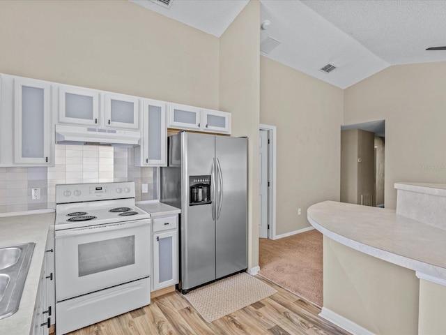 2977 Kokomo Loop, Haines City, FL 33844 - kitchen featuring white electric stove, stainless steel fridge with ice dispenser, under cabinet range hood, vaulted ceiling, and light countertops